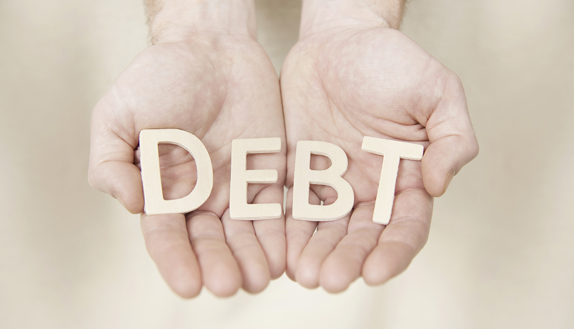 hands holding letters that spell out debt