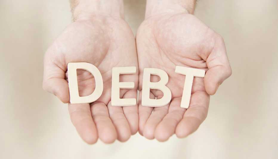 hands holding letters that spell out debt