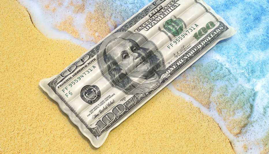 a flotation raft that looks like a hundred dollar bill sits at the edge of an ocean