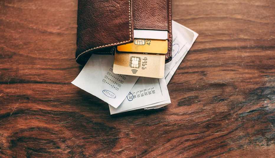 a leather wallet on a table with credit cards and receipts hanging out of it a leather wallet on a table with credit cards and receipts hanging out of it