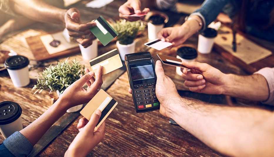 Hands holding out credit cards to split the bill at a restaurant