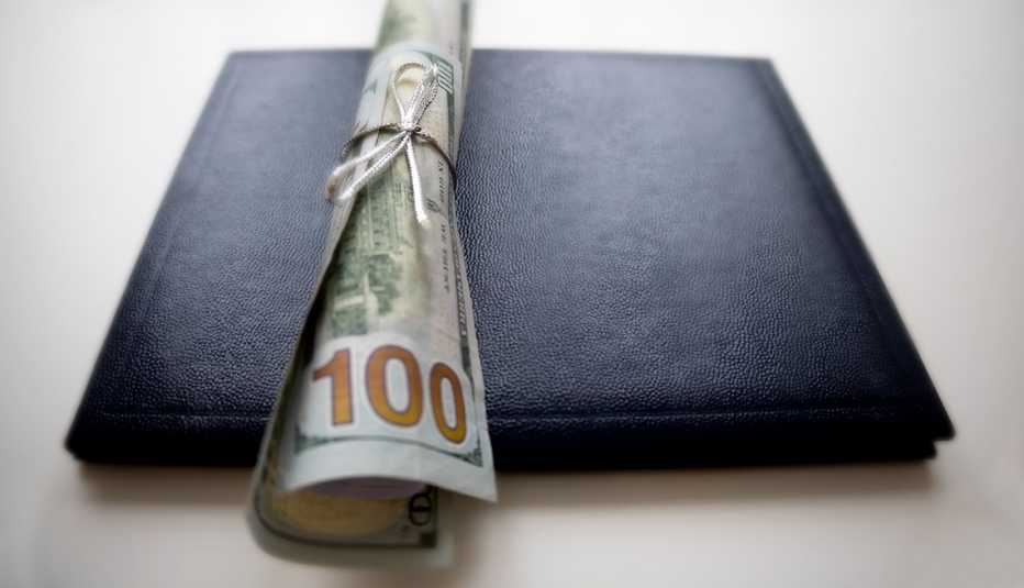 a graduation mortarboard with a hundred dollar bill wrapped up on top of it
