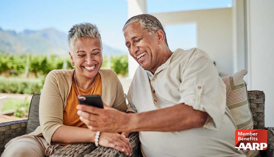 AARP member couple looking at benefits on the their mobile phone while sitting out on a their patio