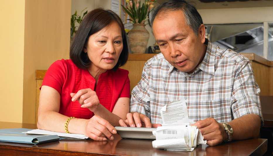 A couple sitting at a table reviewing receipts 