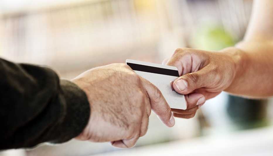 close up of two different hands holding onto opposite edges of a credit card 