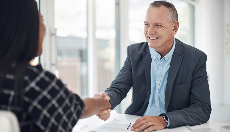 a boss and an employee shake hands in a brightly lit office
