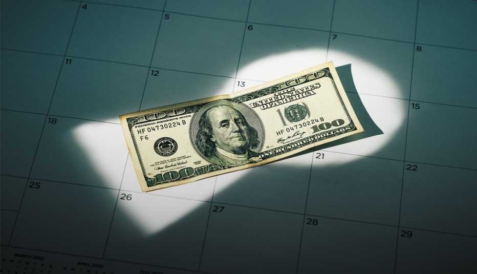 a hundred dollar bill on a calendar with a light on it shining through a keyhole