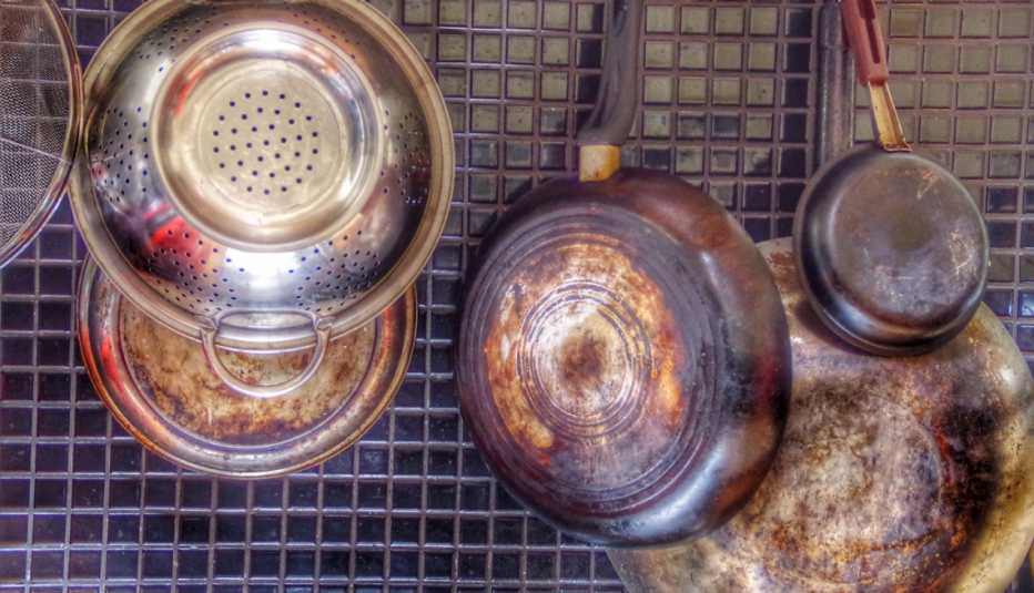 old used pots and pans hanging from a wire rack