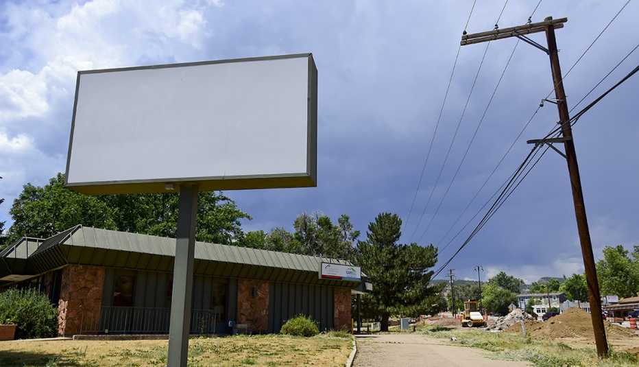 exterior of a vacant small bank building with a big blank sign where the bank name used to be 