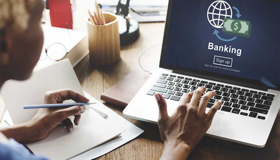 Profile of a woman with hands on laptop keyboard signing up for banking services