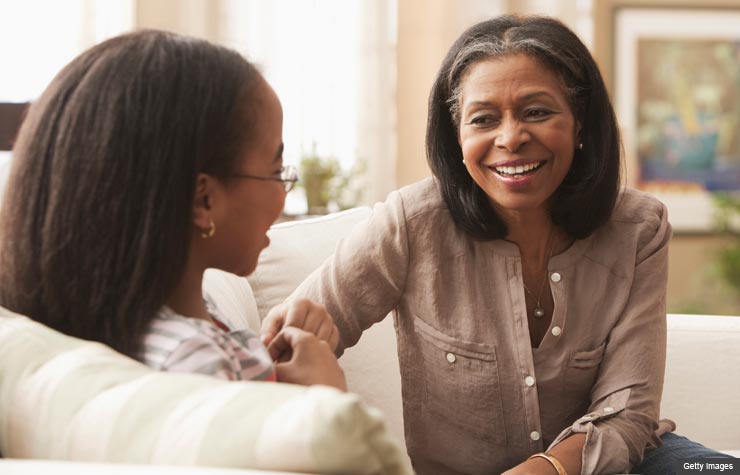 Grandmother talking to granddaughter on couch.