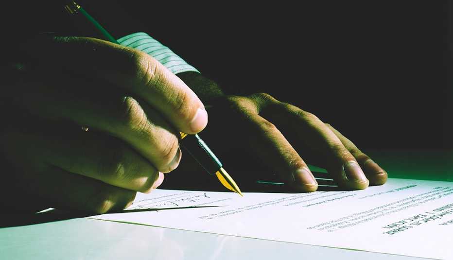 Person signing papers with dark background