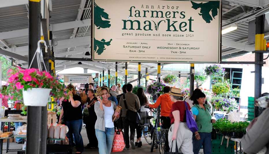 shoppers under a metal shed structure at the ann arbor farmers market