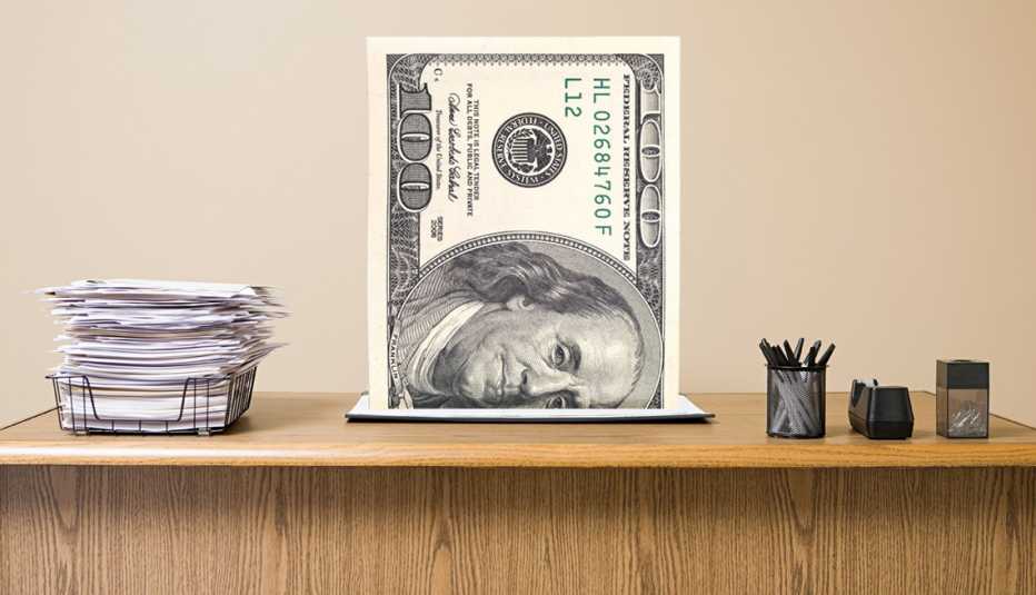 an office desk with a 100 dollar bill emerging from it