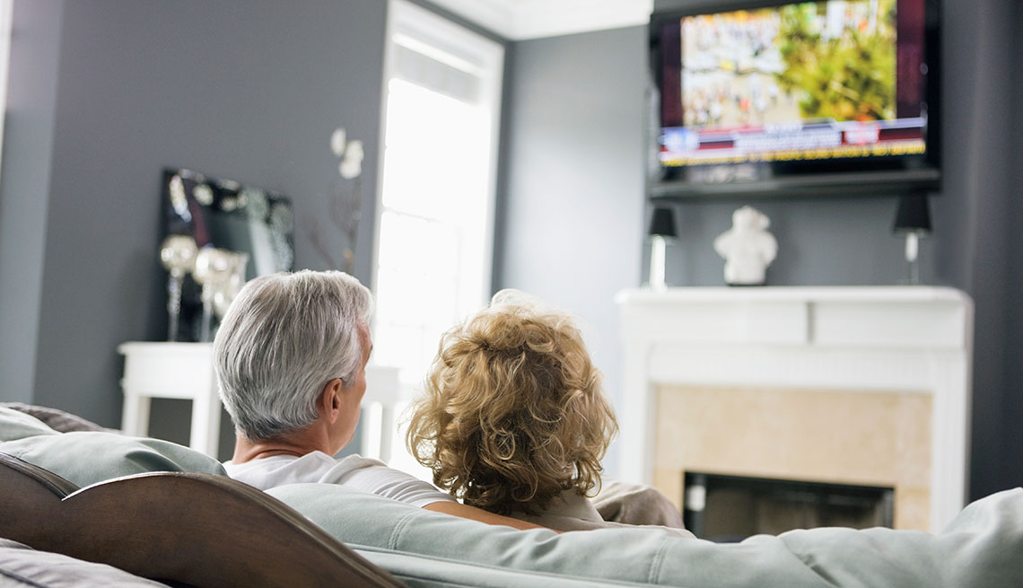 Back of heads of Man and Woman watching television in a living 