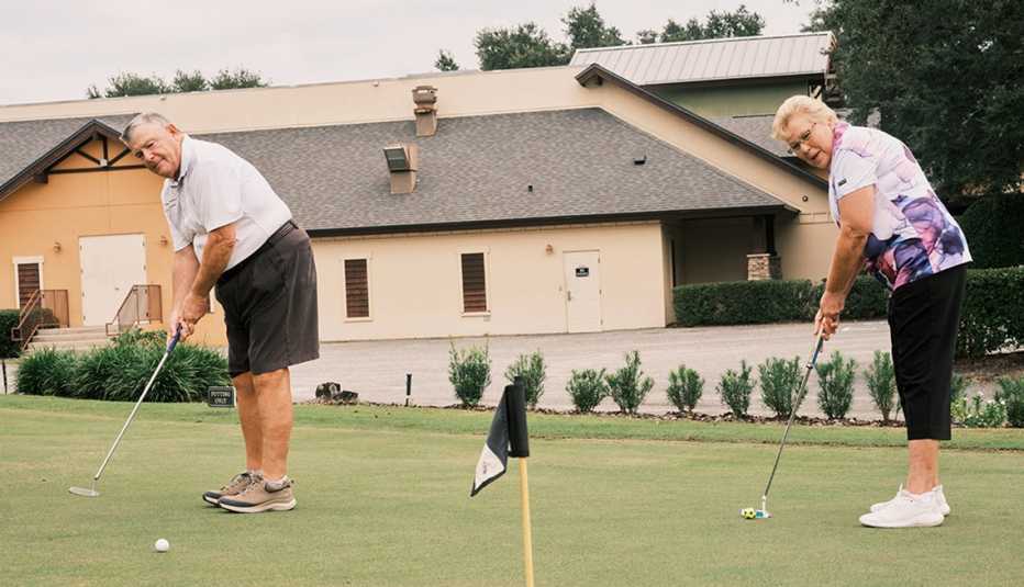 john and marva tetting pose for photos with gold clubs on a putting green near their home in florida
