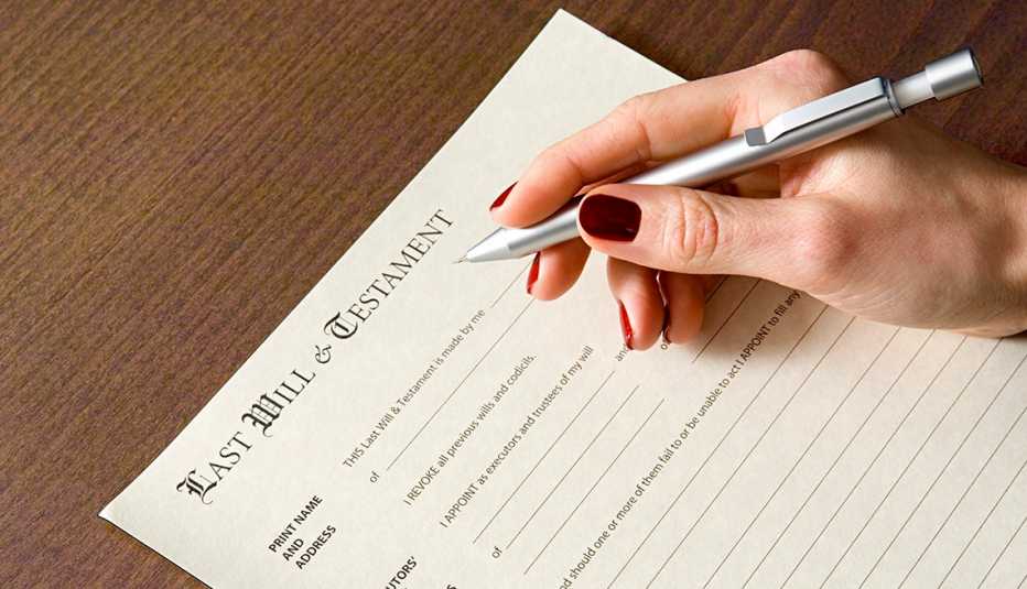 A women's hand holds a pen over a blank last will and testament document