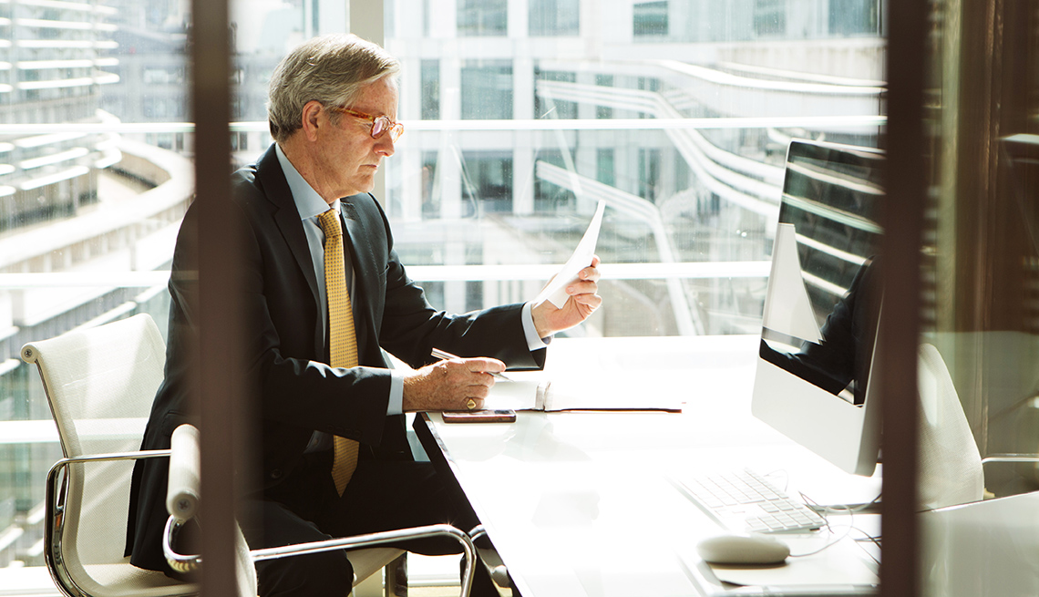 man looking at a piece of paper in front of a computer