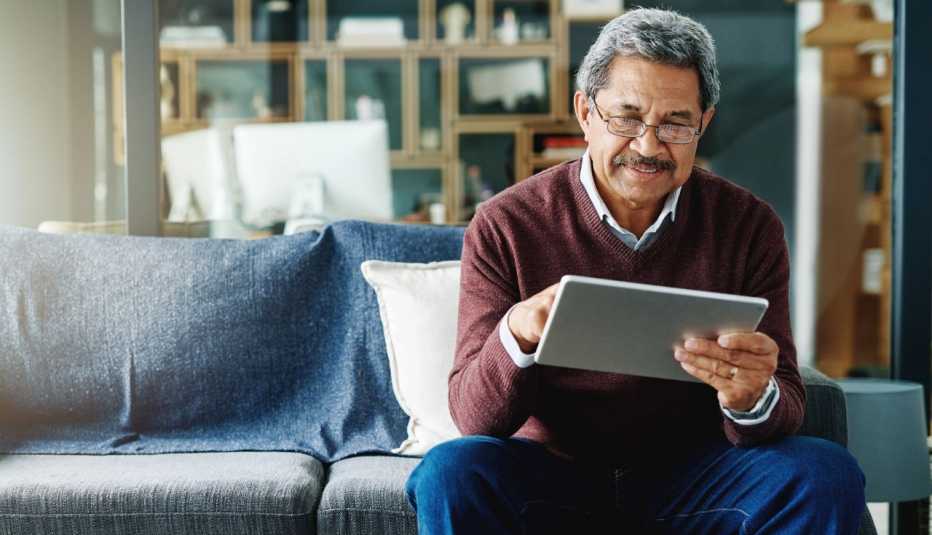 an older man uses a tablet from home