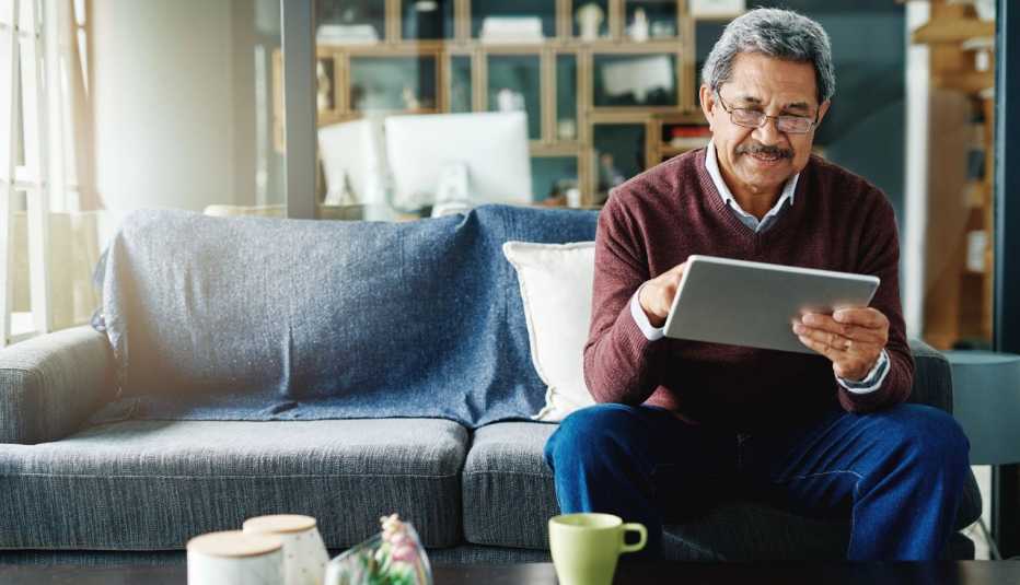 an older man uses a tablet from home