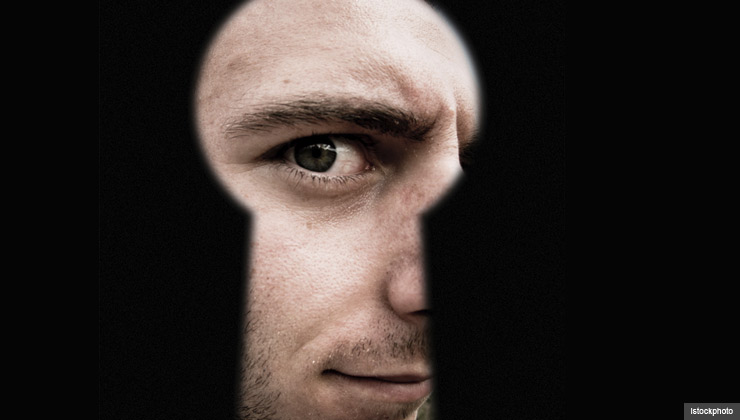 A man peers through a keyhole representing door-to-door sales scams. A man peers through a keyhole representing door-to-door sales scams.
