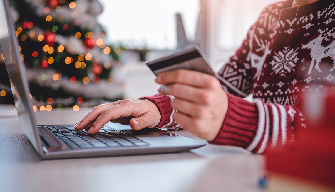 Women wearing red sweater shopping online and using credit card at home office