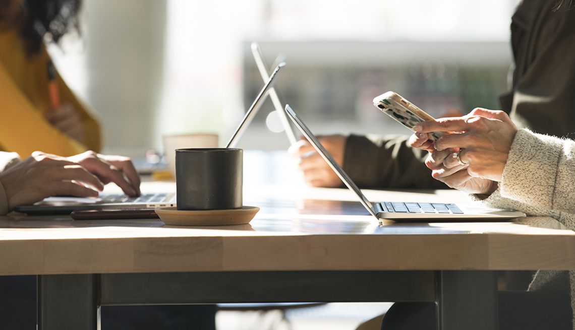 Close up of group of people using smart phones and laptops in a public setting
