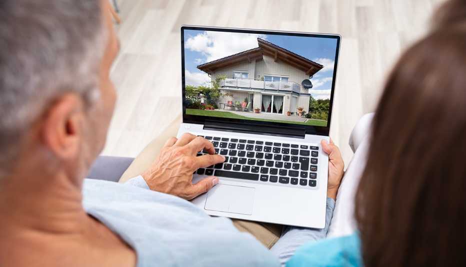 Couple looking at house online on laptop at home