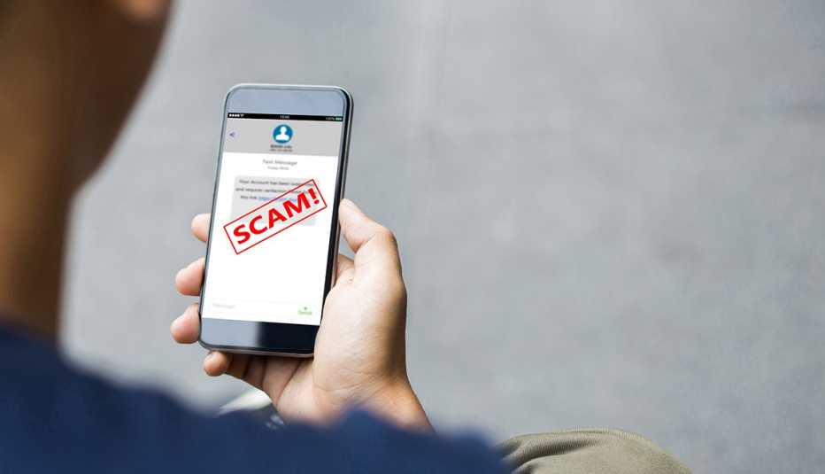 person looks at phone with a scam alert on it