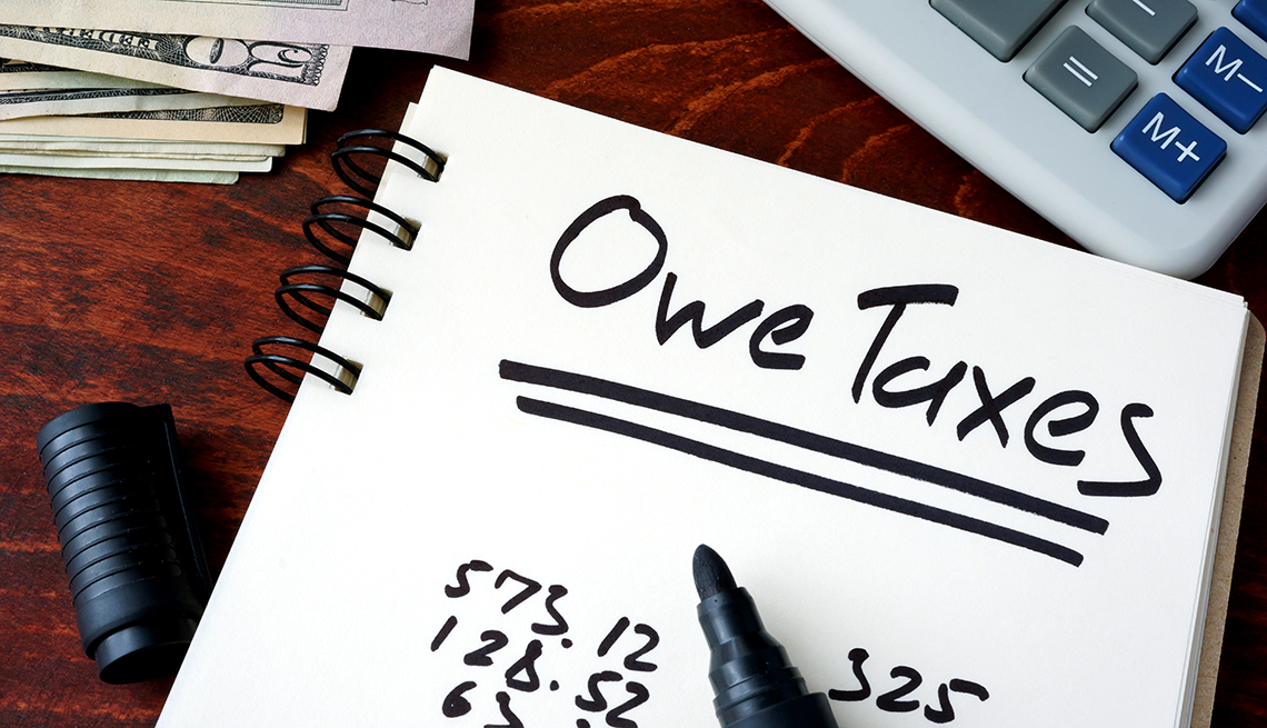 Notepad with sign Owe Taxes on a wooden background.