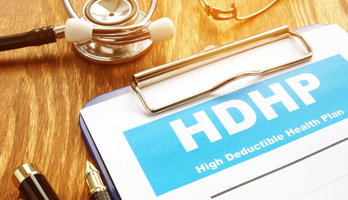 HDHP, High Deductible Health Plan written on paper clipped to board on desktop with stethoscope and pen