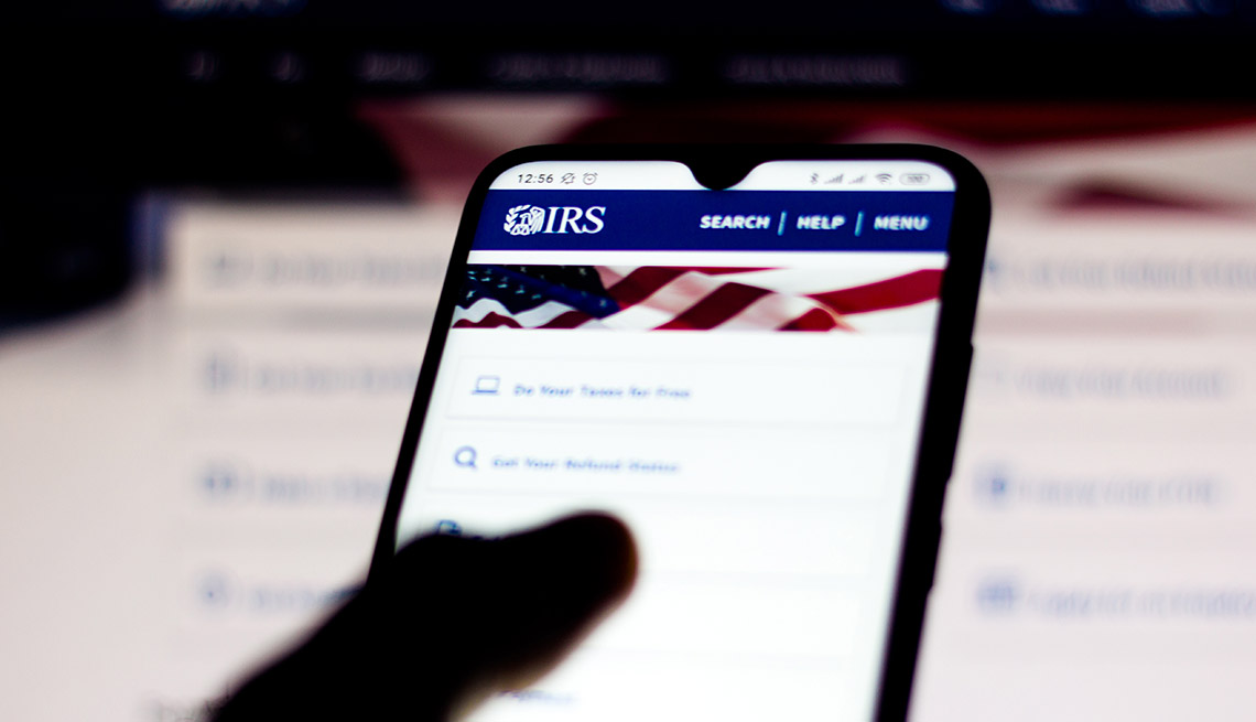 close up silhouette of a thumb on a mobile phone device displaying the IRS website