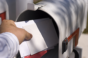Male human hand pulling white envelopes from outdoor mailbox Male human hand pulling white envelopes from outdoor mailbox