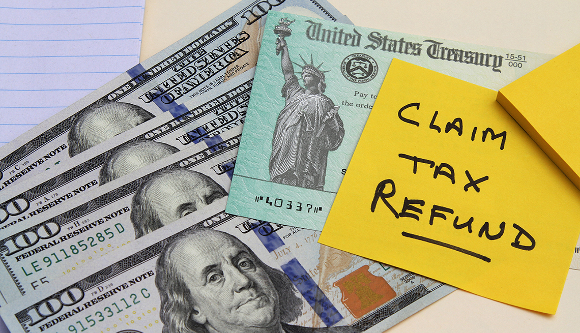 display of IRS tax refund check with note to claim tax refund and 100 dollar bills
