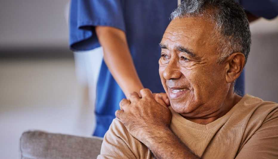 a man sitting on a couch holding a woman's hand on his shoulder