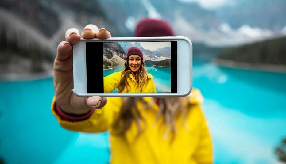 woman in a yellow jacket taking a cell phone selfie