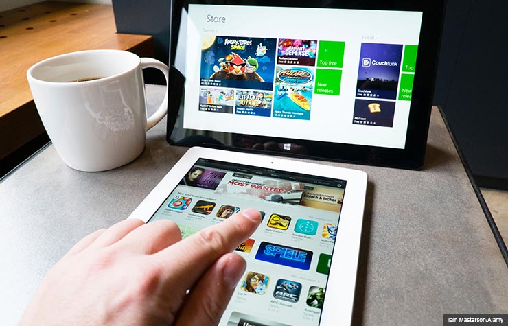 Man using iPad and Microsoft Surface. Digital tablet buying guide. (Iain Masterson/Alamy) Man using iPad and Microsoft Surface. Digital tablet buying guide. (Iain Masterson/Alamy)
