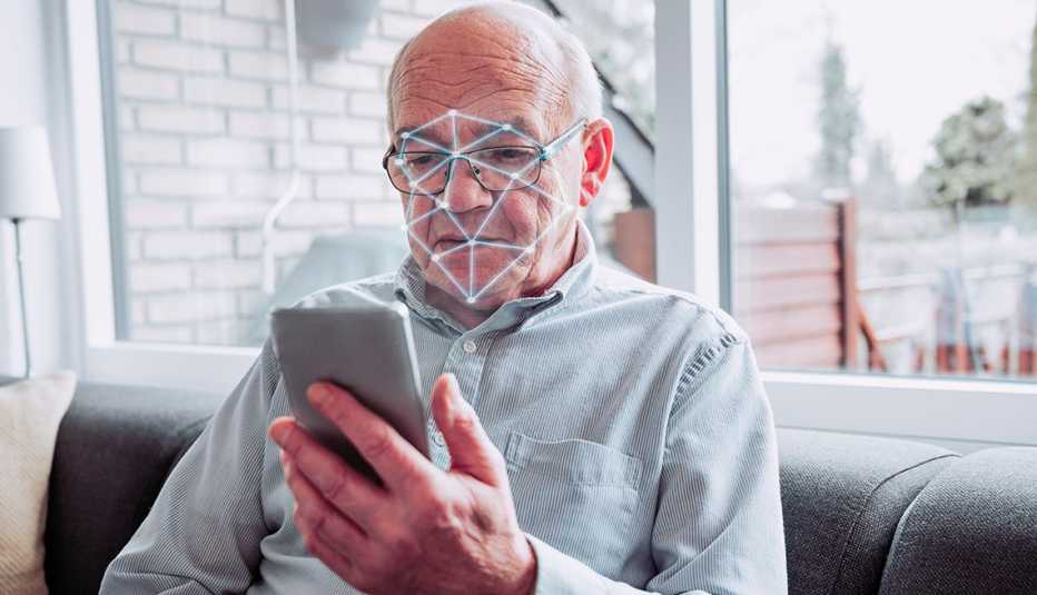 a man holds a smart phone and it performs a scan of his face