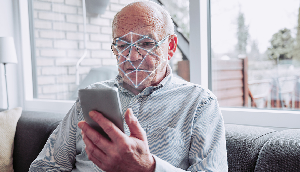 a man holds a smart phone and it performs a scan of his face