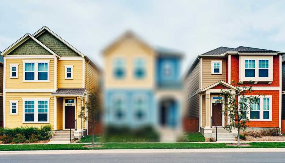 a view of three houses from the street and the middle one is blurred out