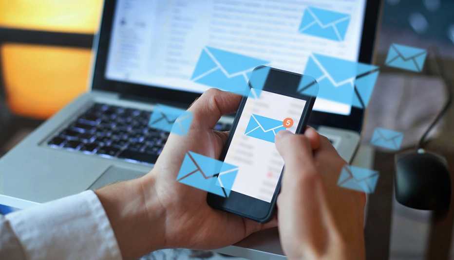 a pair of hand on a smartphone, along with abstract images of email icons floating around in front of a computer screen