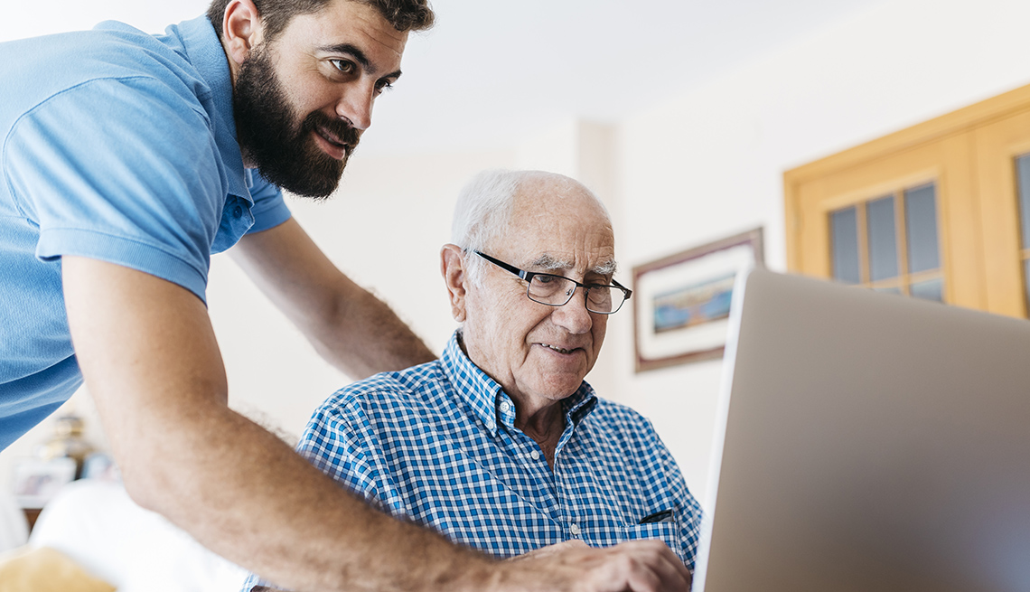 Grandson teaching his grandfather to use the computer and surf the internet.