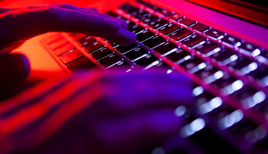 hands on a keyboard hands typing on a keyboard under a red and purple light
