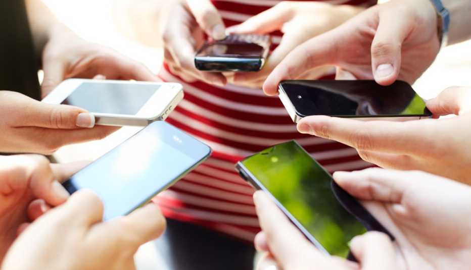 a circle of hands holding different models of cell phones