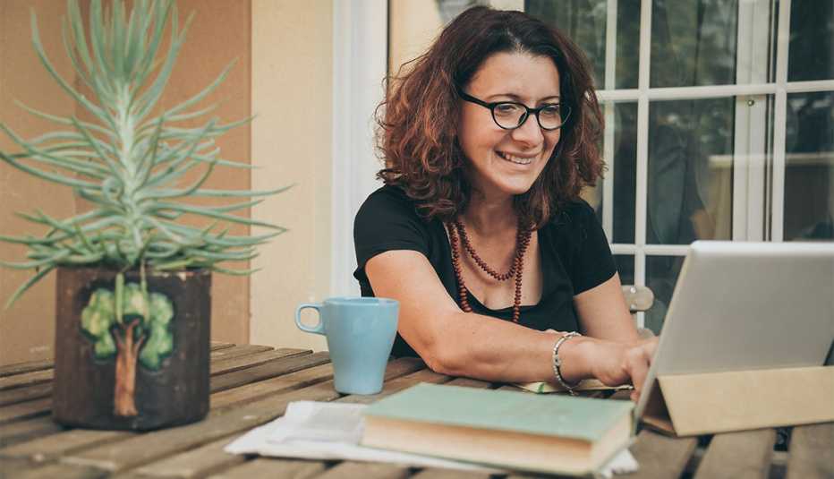 woman studying at home with books, newspaper and digital tablet