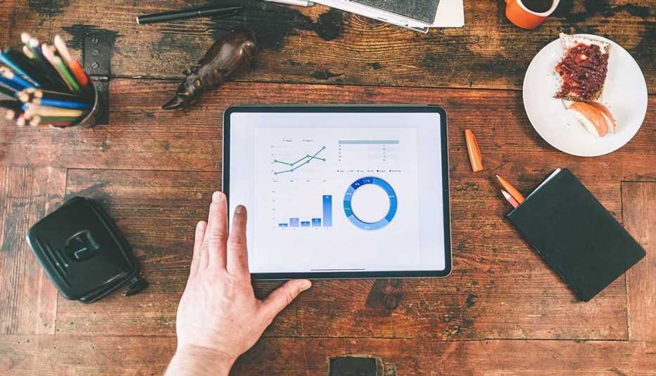 Man reviewing statistics on a tablet over a wooden desk