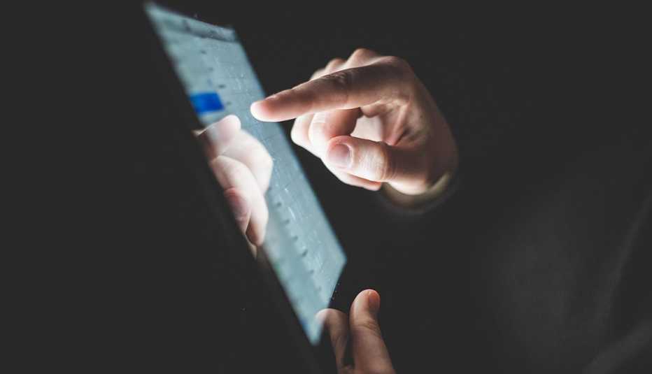 a man's hand points to something on a tablet screen
