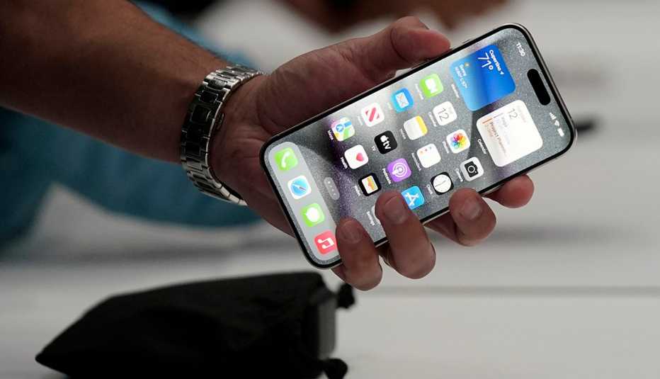 a man wearing a watch holds an iphone 15 pro during an event on the apple campus