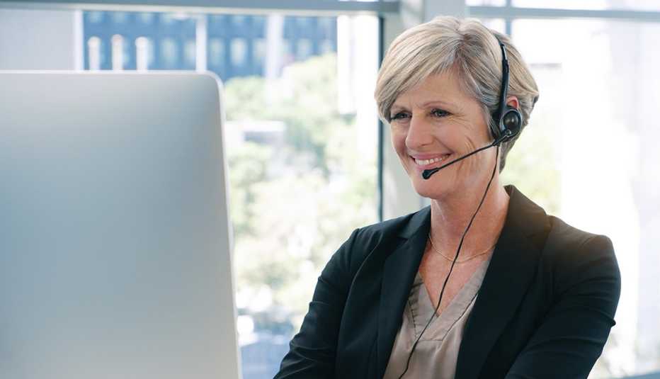 Shot of a mature businesswoman wearing headphones while working on a computer in an office