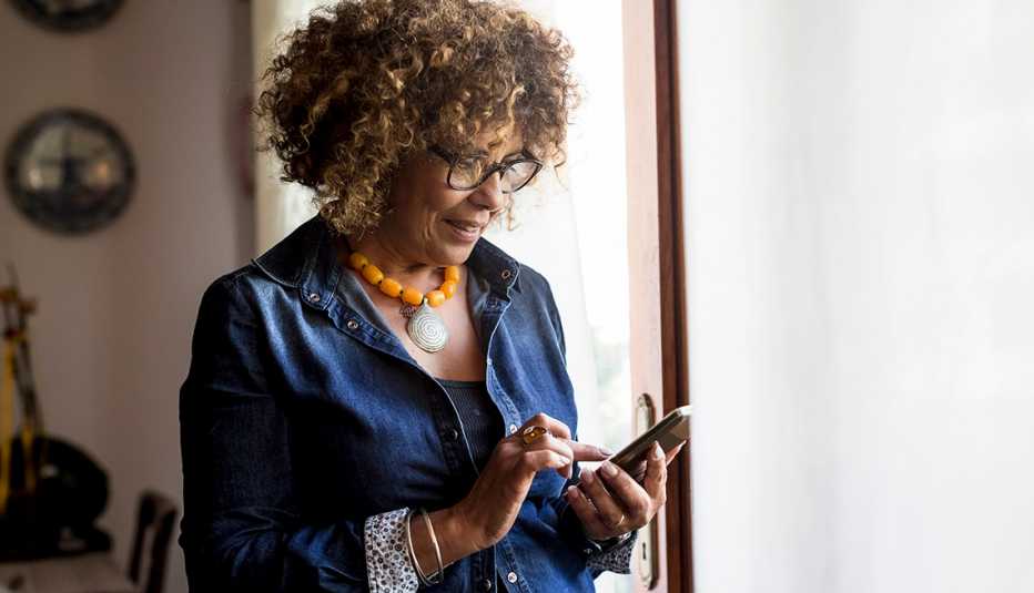 Woman looking at her smartphone near a window Woman looking at her smartphone near a window